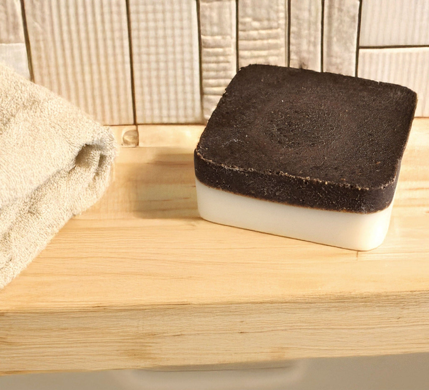 Lavender exfoliating soap bar with upcycled coffee grounds and natural oils on wooden surface next to beige towel