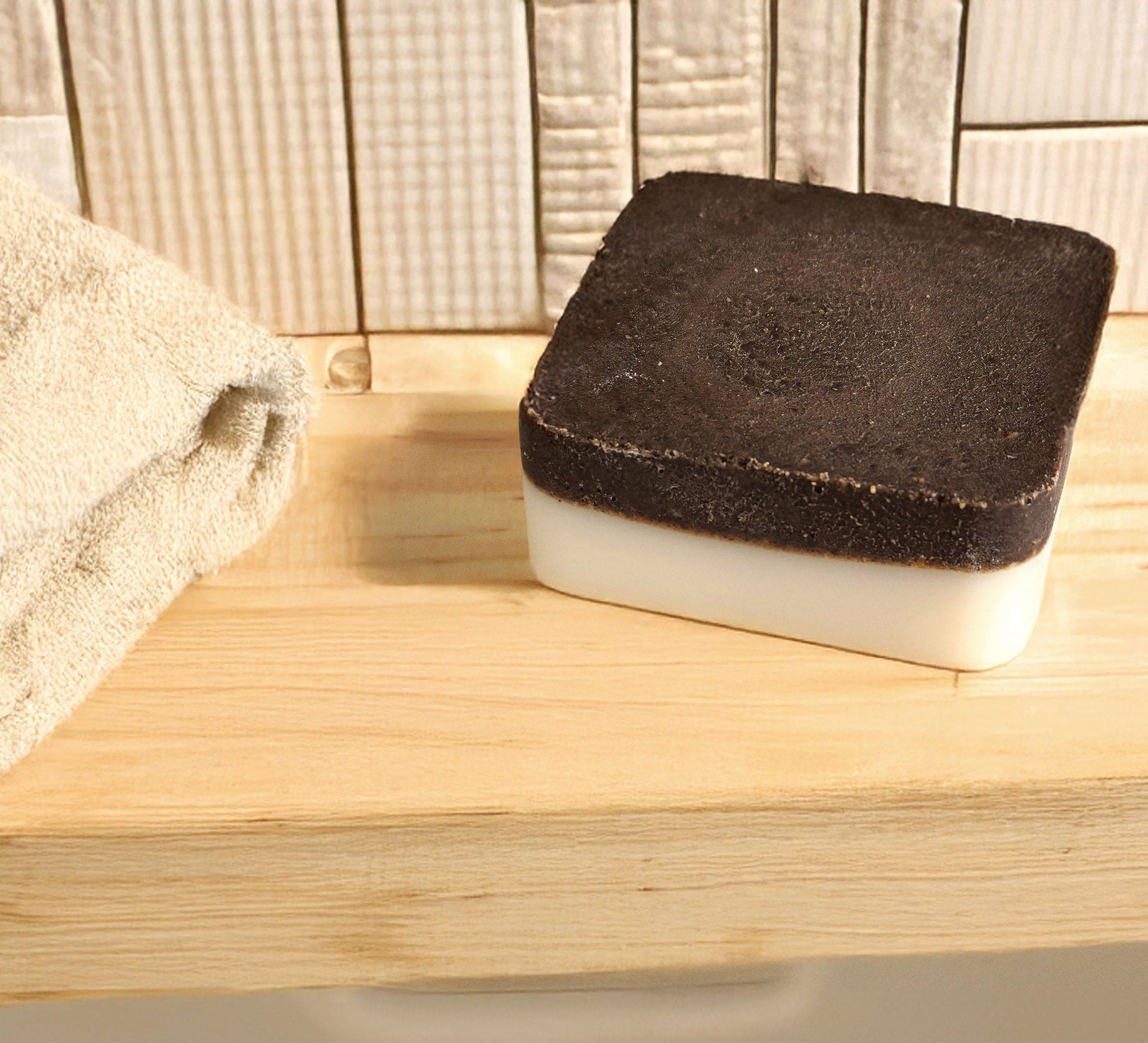 Lavender exfoliating soap bar with upcycled coffee grounds and natural oils on wooden surface next to beige towel